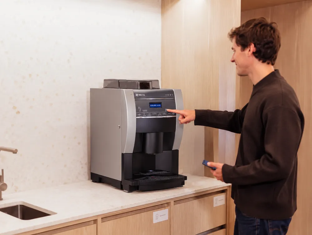 Persona sirviéndose un café en la máquina de una oficina