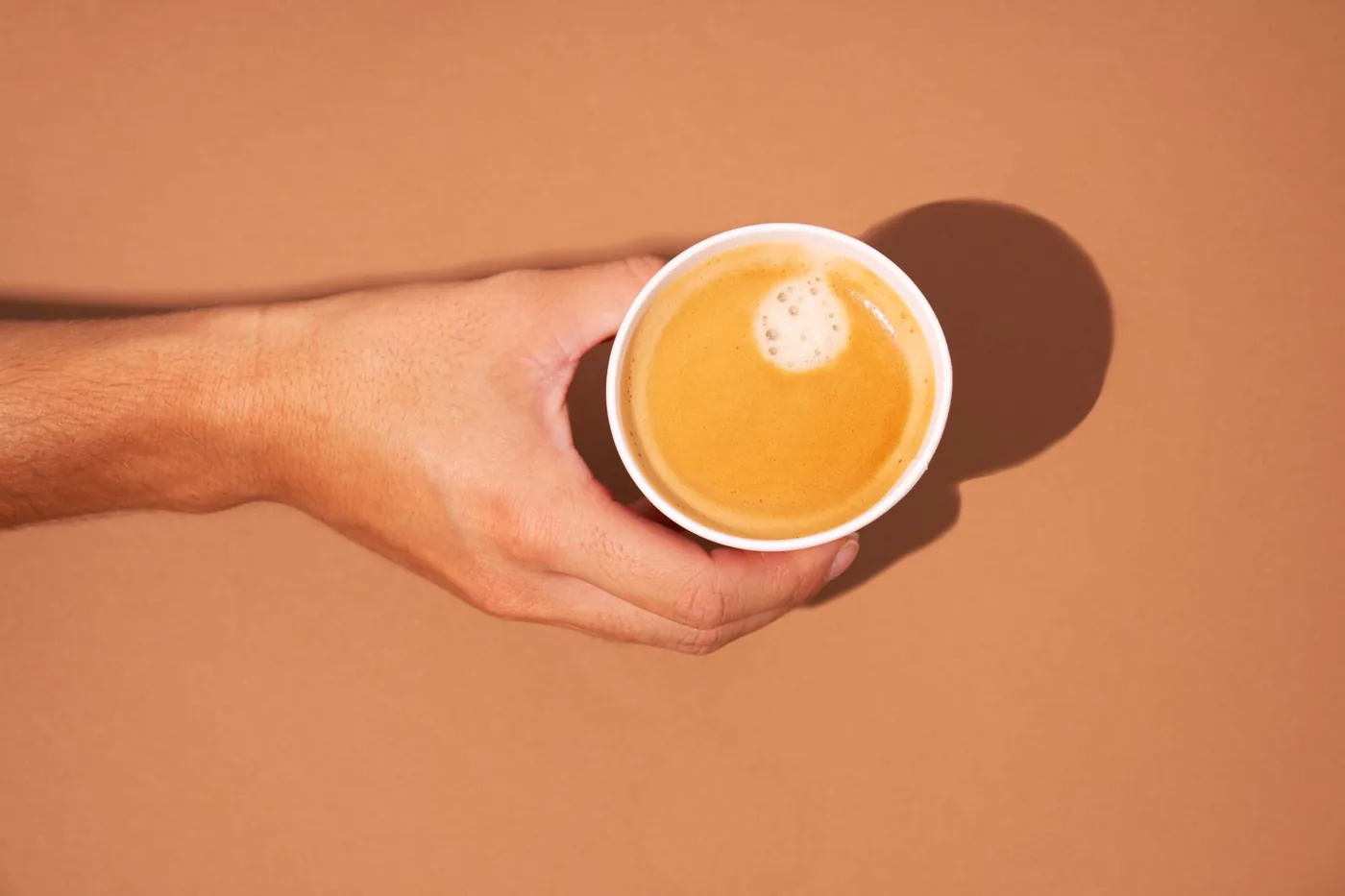 Vaso de café recién hecho sostenido en la mano